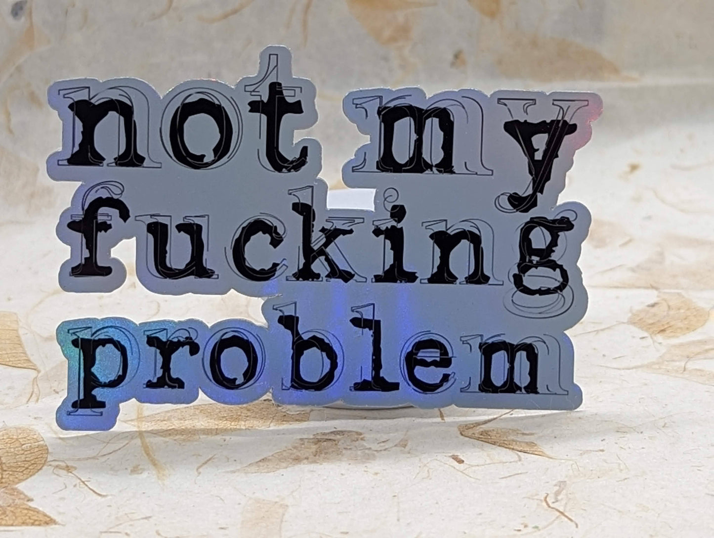 Not My Fucking Problem holographic vinyl sticker, alternate angle showing color shift - SoCuteINeedOneToo